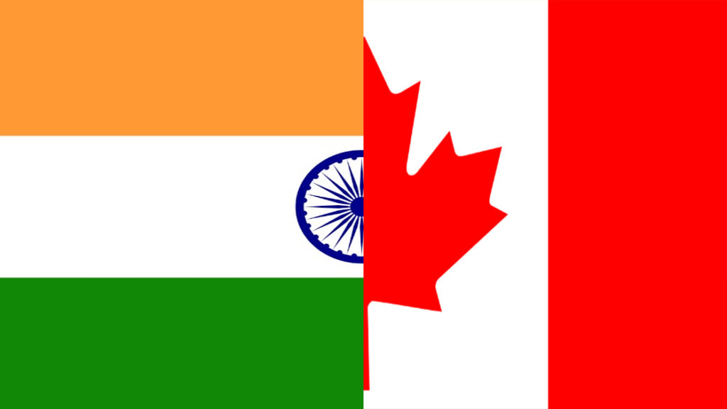 A mash-up of the flags of India and Canada. The Indian flag, with orange, white, and green stripes sits on the left of the image, while the Canadian flag, featuring red and white colours, sits on the right